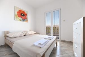 a white bedroom with a bed and a window at Costa apartment with private pool in Preko +31 photos
