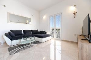a living room with a black couch and a tv at Costa apartment with private pool in Preko
