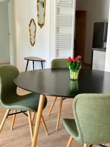 a black dining room table with green chairs and a vase of flowers at Ferienwohnung 'kommodig' nahe der Eider in Delve