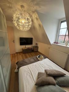 a bedroom with a large bed and a chandelier at Escapade chaleureuse in Sequedin