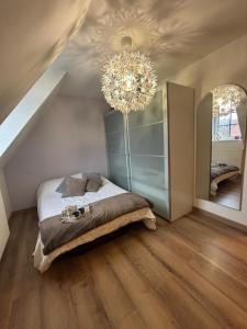 a bedroom with a bed and a chandelier at Escapade chaleureuse in Sequedin