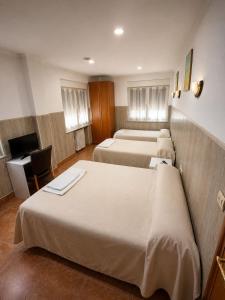 a hotel room with three beds and a television at Agarimo in Trapagaran