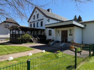 a white building with a fence in front of it at Pension & Gaststätte Bauernstube in Heinsdorfergrund