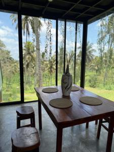 a wooden table with two chairs and a vase on it at Hideout Boomeru in Matale