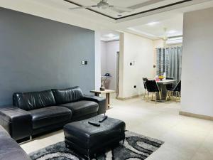 a living room with a black leather couch and a table at T-Roys Apartments in Accra