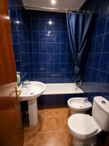 a blue tiled bathroom with a toilet and a sink at Agarimo in Trapagaran +12 photos