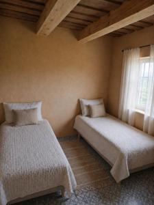 two beds in a room with a window at Kregžlės kaimas in Skirlėnai