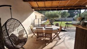 a patio with a table and chairs and a swing at Mas d'Andiol in Plan-dʼOrgon