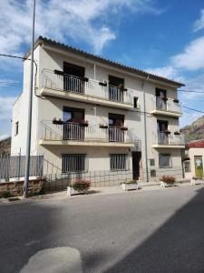a white apartment building with balconies and a street at Casa Bajo Castillo in Montán