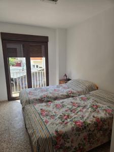 a bedroom with two beds and a window with a balcony at Casa Bajo Castillo in Montán