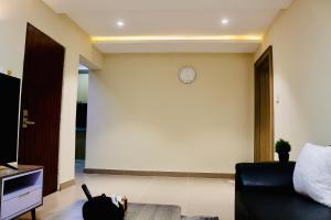 a living room with a couch and a clock on the wall at House 10 Apartments in Abuja