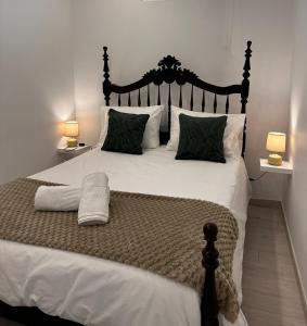 a bedroom with a large white bed with two lamps at Casa Maria Olímpia in Nazaré