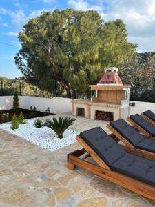a patio with two lounge chairs and a fireplace at Villa Pano Salamina in Ambelákia