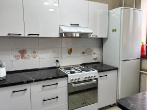 a white kitchen with a stove and a refrigerator at Starpath Homestay in At-Bashy