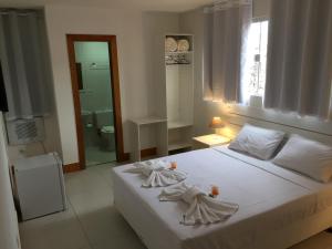 Un dormitorio con una cama blanca con toallas. en Pousada Vila Forte, en Cabo Frío