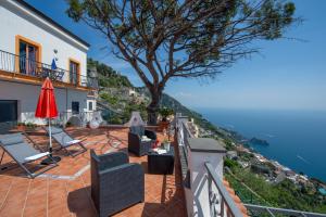 a patio with chairs and a tree overlooking the water at Calipso Residence in Furore