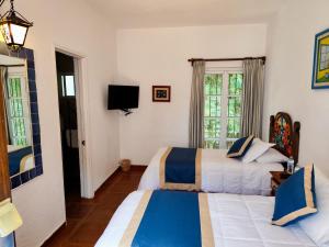 a hotel room with two beds and a television at Casa de las Conchas Cuernavaca in Cuernavaca