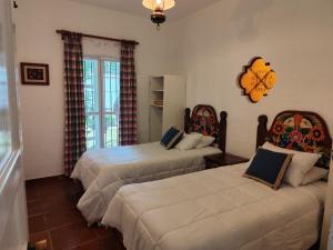 a bedroom with two beds and a clock on the wall at Casa de las Conchas Cuernavaca in Cuernavaca