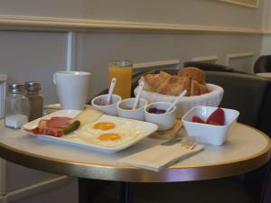 a breakfast tray with eggs and bread and fruit on a table at Appart Hotel Spa Perpignan in Perpignan