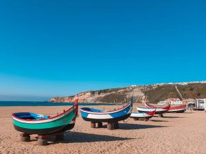 a row of boats sitting on a sandy beach at Casa Maria Olímpia in Nazaré