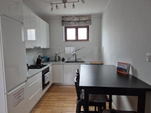 a kitchen with white cabinets and a black table at Fay-home in Odorheiu Secuiesc