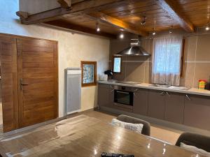 a kitchen with a wooden table and a wooden door at La Fenière in Roubion