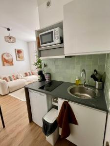 a kitchen with a sink and a couch in a room at Votre cocon parisien in Bagnolet