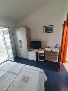 a bedroom with a bed and a desk and a refrigerator at Marica Dedić in Barbat na Rabu