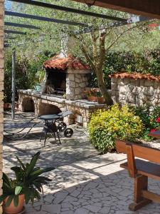 a patio with a stone fireplace and a table at Marica Dedić in Barbat na Rabu