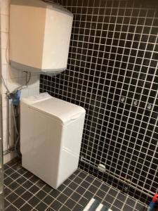 a white toilet in a black tiled bathroom at Magsjön in Surahammar +11 photos