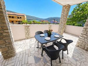 a patio with a table and chairs on a stone patio at Apartments Renato Mužić Cres in Cres