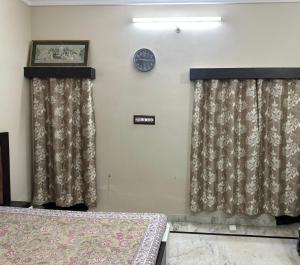 a bedroom with two beds and a clock on the wall at Dj's home stay in Jodhpur