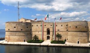 a large building with flags in front of the water at Casa Vacanze da Melina in Taranto