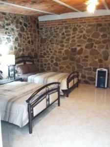 two beds in a room with a stone wall at Rancho alegre in Jocotepec