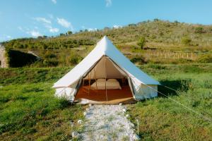 a white and blue tent in a field at Aluna Camp in Nudo +10 photos