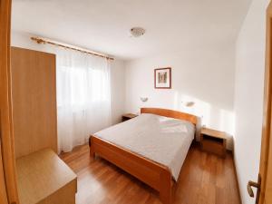 a small bedroom with a bed and a window at Apartments Renato Mužić Cres in Cres