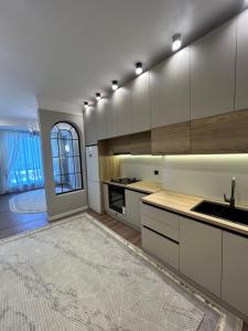 a kitchen with white cabinets and a large rug at Lola in Osh