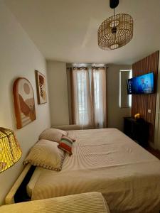 a bedroom with two beds and a flat screen tv at Votre cocon parisien in Bagnolet