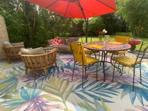 a patio with a table and chairs and an umbrella at Le Cap Saint Jacques Chambre d hôtes proche de bayeux à 15 mn idéal plages du débarquement in Putot-en-Bessin