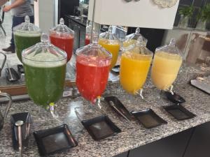 four wine glasses filled with different colored drinks on a counter at Hotel Flor de Minas in Uberaba