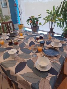 a table with plates and glasses on top of it at Les Chambres de Kérity in Penmarch