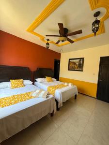 a bedroom with two beds and a ceiling fan at HotelJosefadeMaria in Izamal