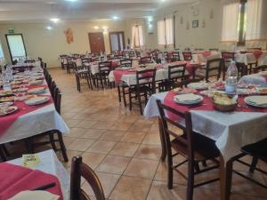 a room filled with tables and chairs with red tablecloths at Agriturismo Punta Su Cunventu in Narcao