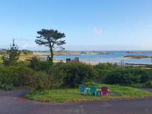 four chairs sitting on the grass near a beach at Chambres d hôtes vue mer au gré des marées Plouguerneau Bretagne in Plouguerneau