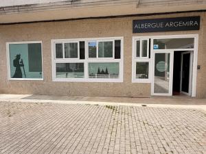 a building with white windows and a person in the reflection at Albergue Argemira - Grupo Arcanos in Caldas de Reis