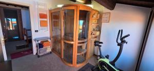 a room with a gym with a wooden cabinet and a treadmill at Skyline Virgilio SUITE sottotetto vista MARE parking in San Marino