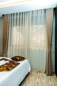 a bedroom with a bed and a window with curtains at Travellers Palace Hotel in Kampala