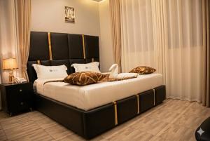 a bedroom with a bed with a black headboard and pillows at Travellers Palace Hotel in Kampala