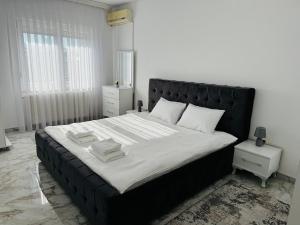 a bedroom with a large bed with a black headboard at Reinas Apartment in Prizren