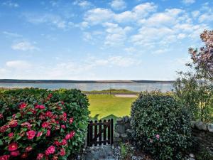 a garden with roses and a fence and a body of water at 1 Bed in Isle Of Arran oc-ca272 in Pirnmill